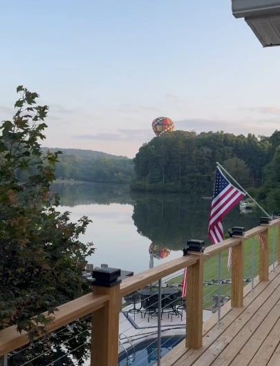 Hot air balloon pilot, dunks the basket in a quiet cottage lake before rising back into sky