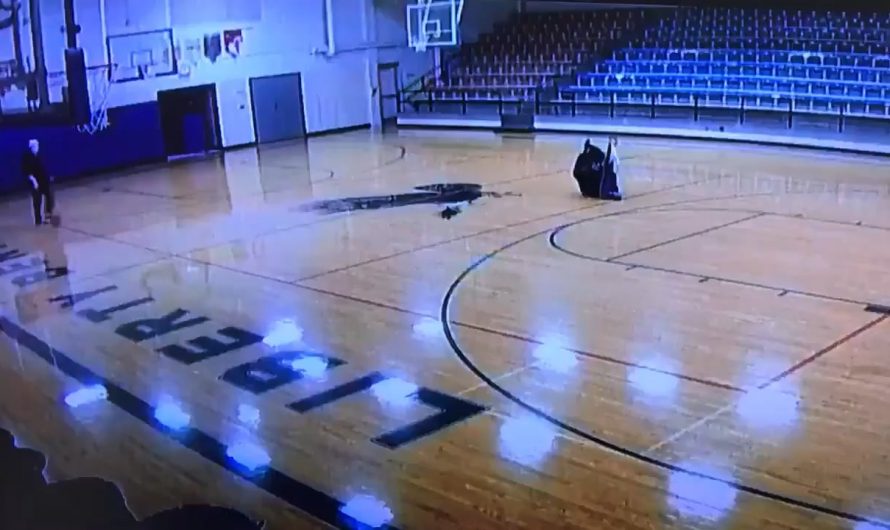 School custodian casually walking through the gym with no one watching but the security camera and making a cool shot look easy