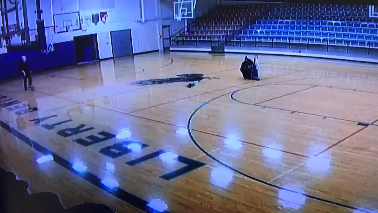 School custodian casually walking through the gym with no one watching but the security camera and making a cool shot look easy