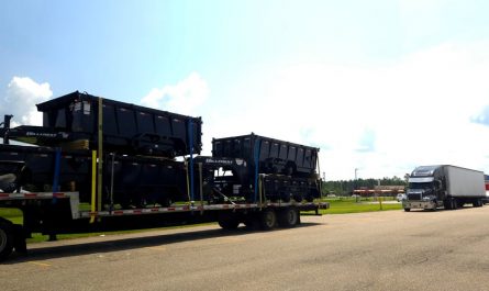 Truck pulling a trailer with two trailers on the trailer and a trailer on top of each trailer on the trailer being pulled by the truck.