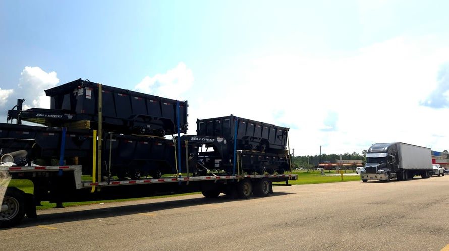 Truck pulling a trailer with two trailers on the trailer and a trailer on top of each trailer on the trailer being pulled by the truck.