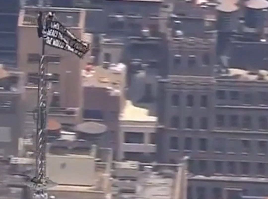 Two climbers have scaled the Empire State Building and unfurled a banner from the top of the spire