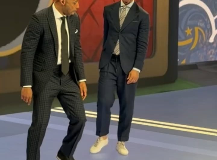 Two football legends casually showing off their skills in a suit and tie