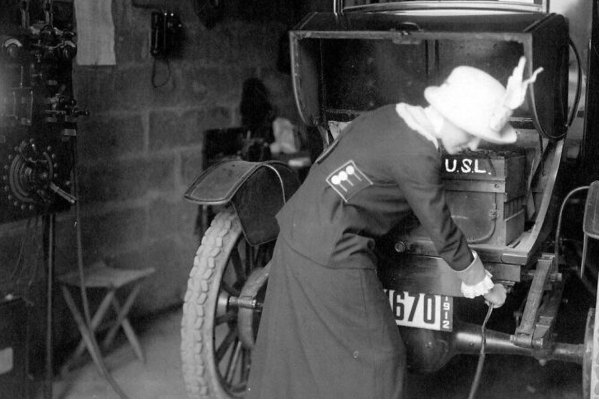 A 1912 shot of a woman plugging in her electric car.