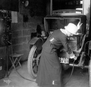 A 1912 shot of a woman plugging in her electric car.